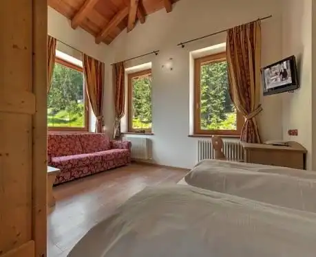 Salottino con divano, travi in legno a vista e TV nella Junior Suite
