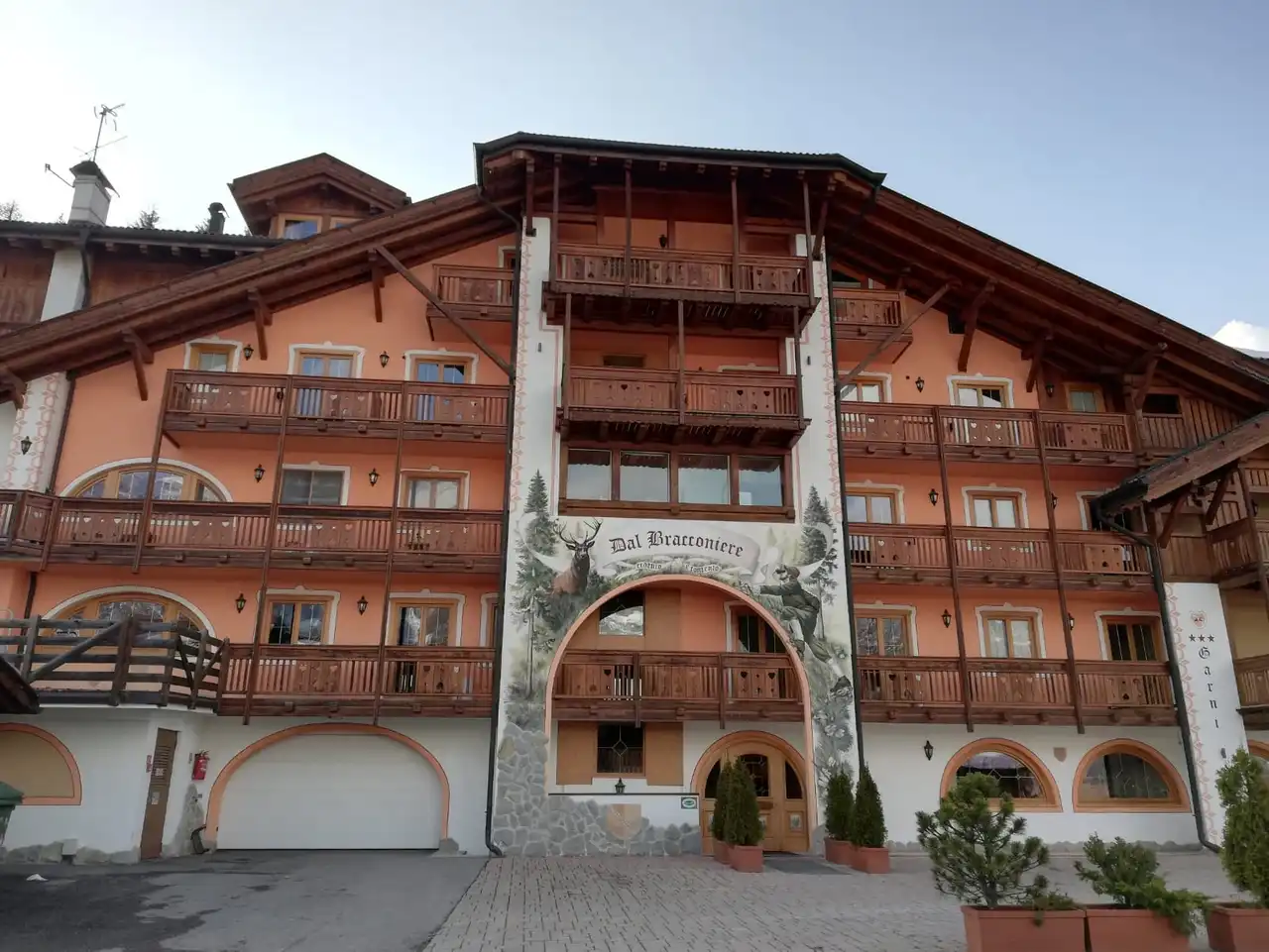L'Hotel Dal Bracconiere con la neve fresca e il sole sulla facciata in legno