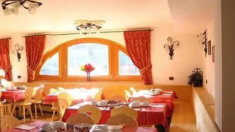 La sala colazioni con le tende rosse e i tavoli in legno