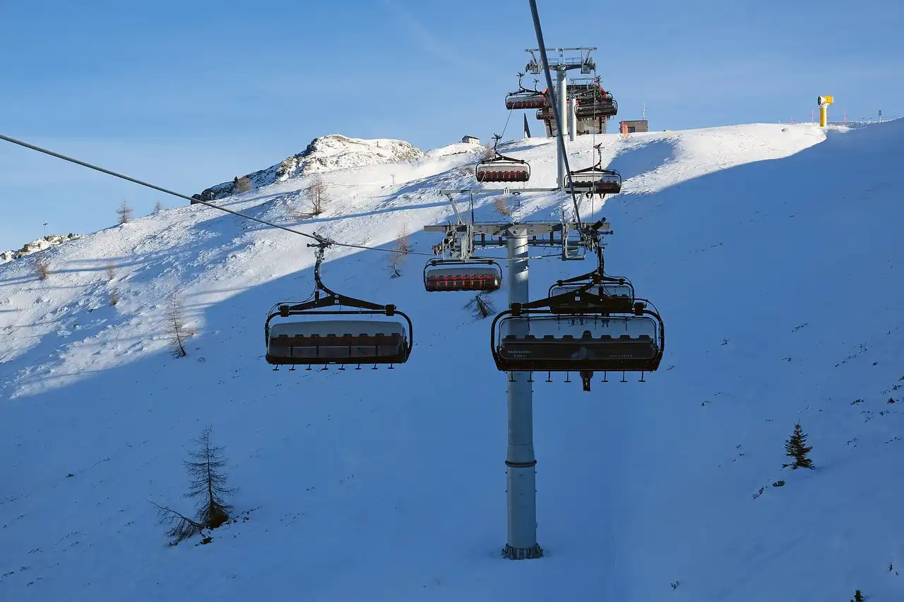 Una seggiovia sopra una pista innevata al sole, con la stazione di monte sul crinale