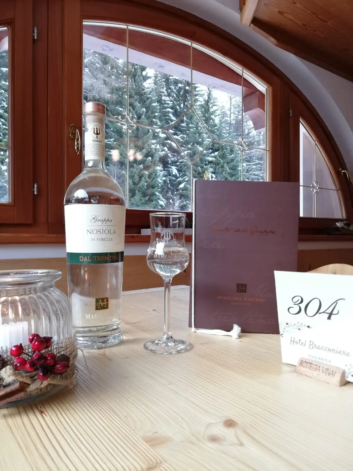 Un tavolo apparecchiato con bicchieri e una bottiglia di vino nella sala dell'hotel