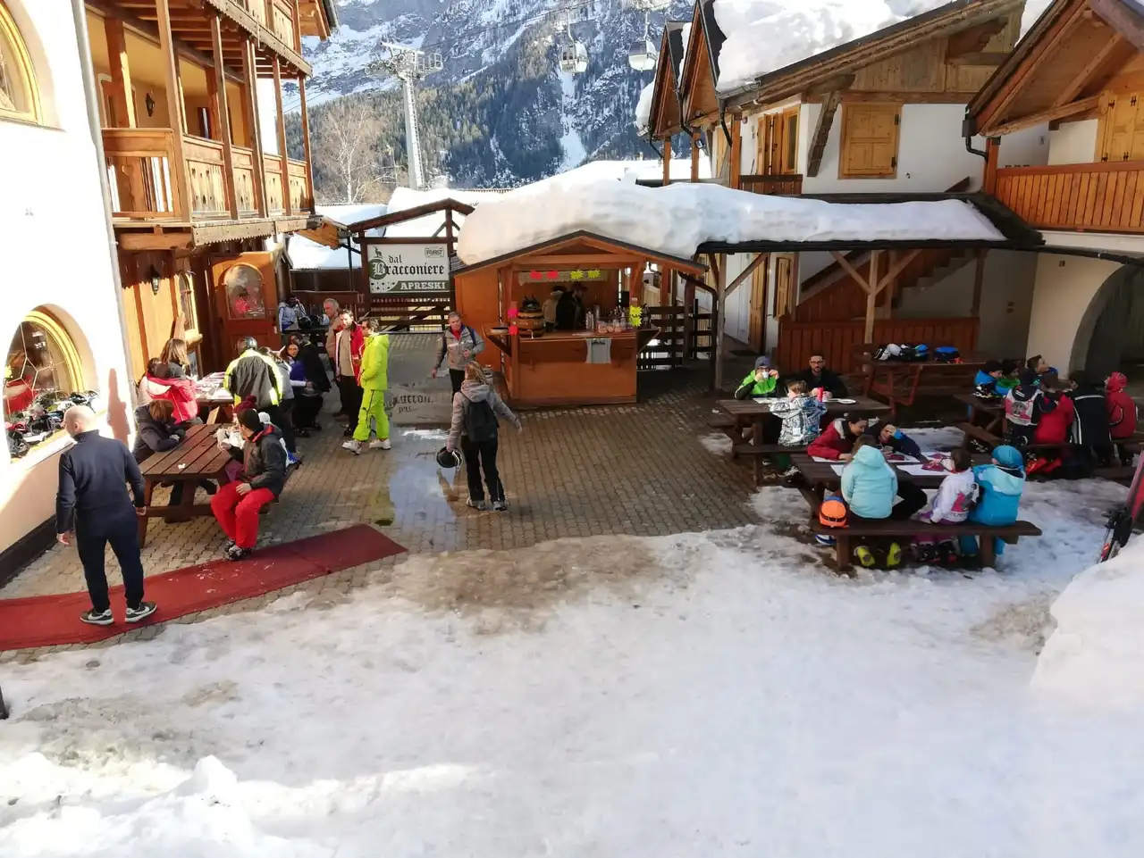 La terrazza solarium dell'hotel piena di sole, con gli sciatori seduti ai tavoli accanto alla pista